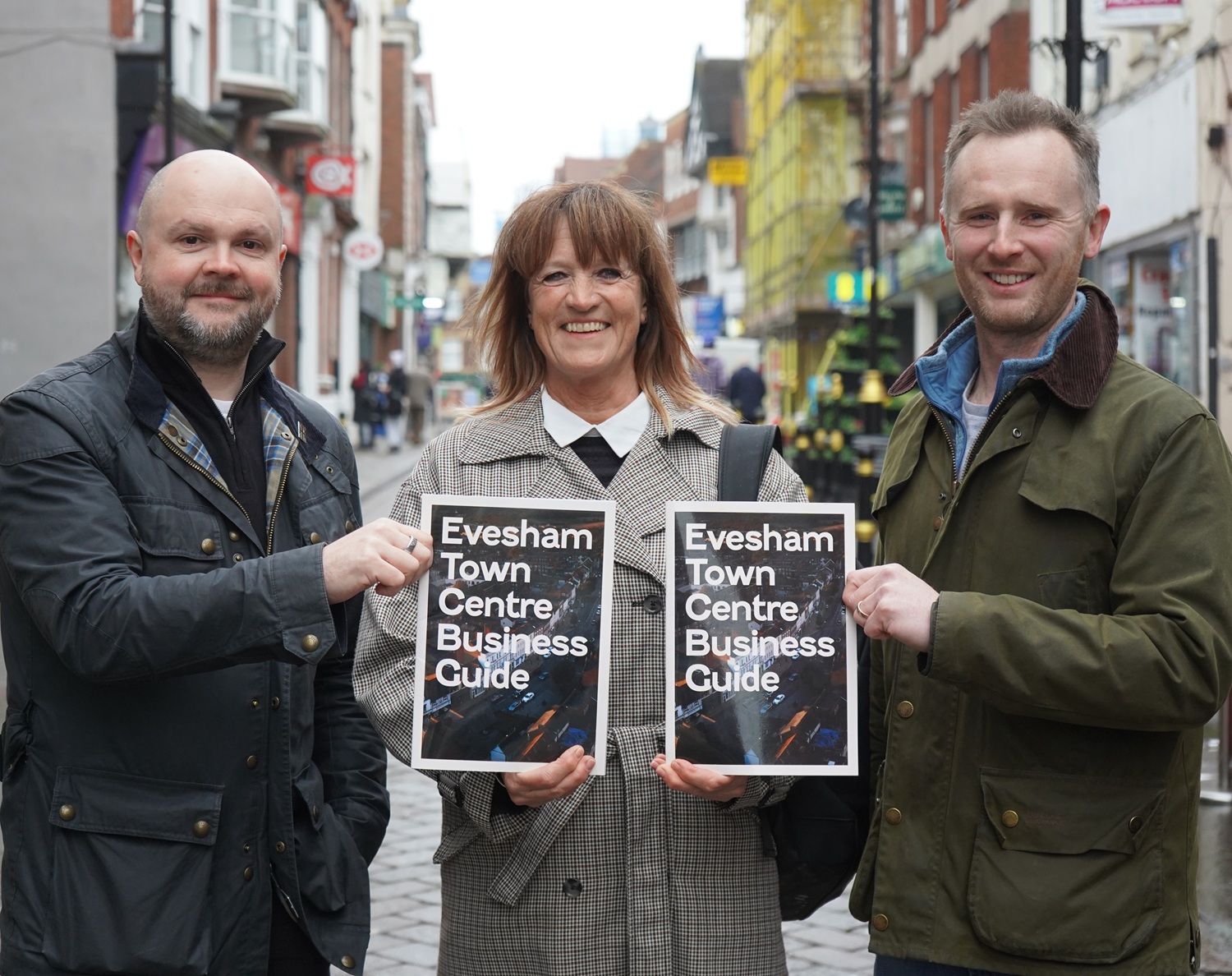 Three people holding a business guide.