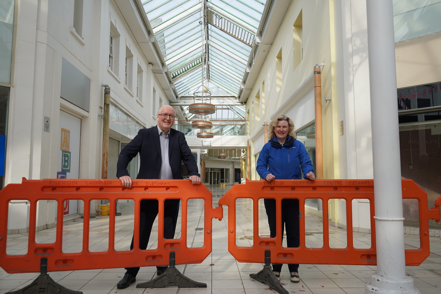 Cllr Morris and Cllr Kearsey leaning on orange barriers inside the Riverside Shopping Centre.