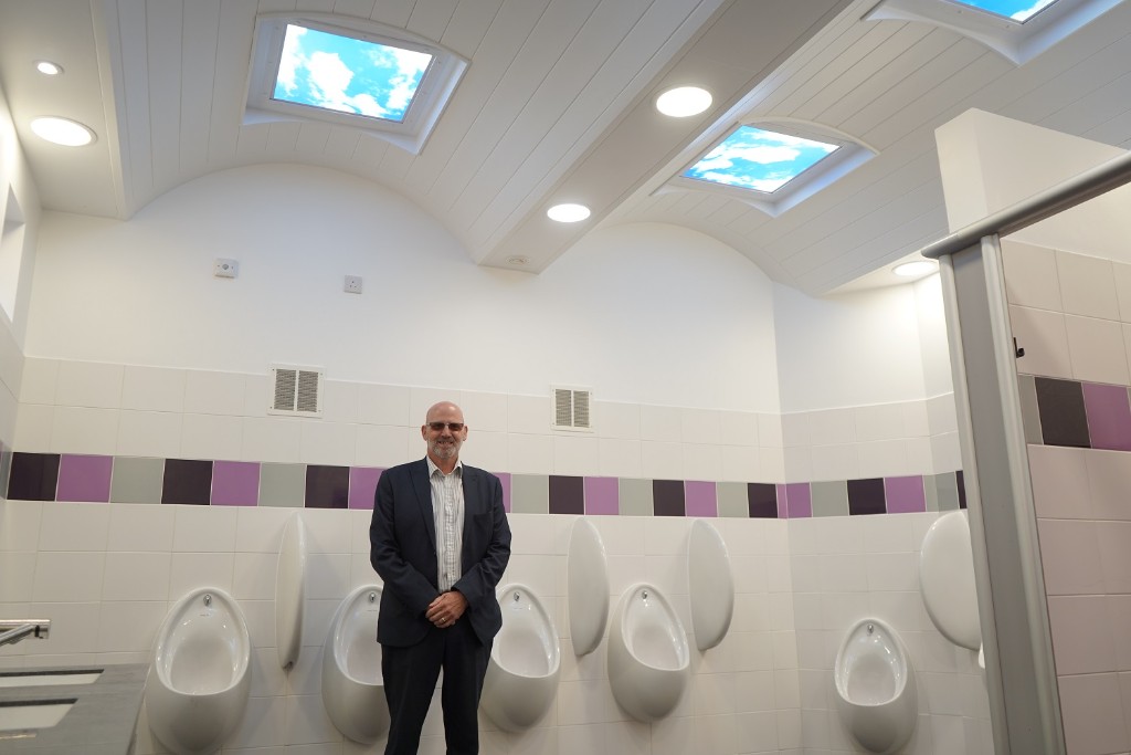 A man stood in front of some urinals.