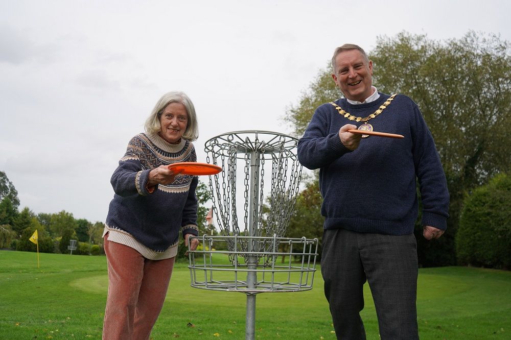 Two people holding disc golf frisbees