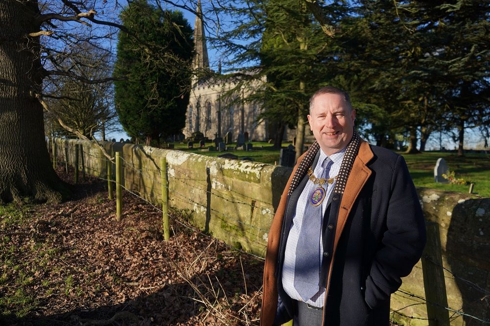 Cllr Robert Raphael stood in front of a church.