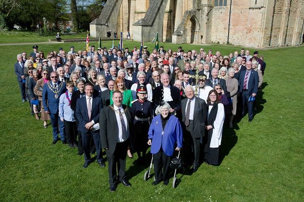 A group of people stood in a V shape in front of Pershore Abbey