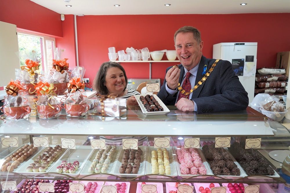 Lisa Broomhead and Cllr Robert Raphael standing behind a counter of chocolate