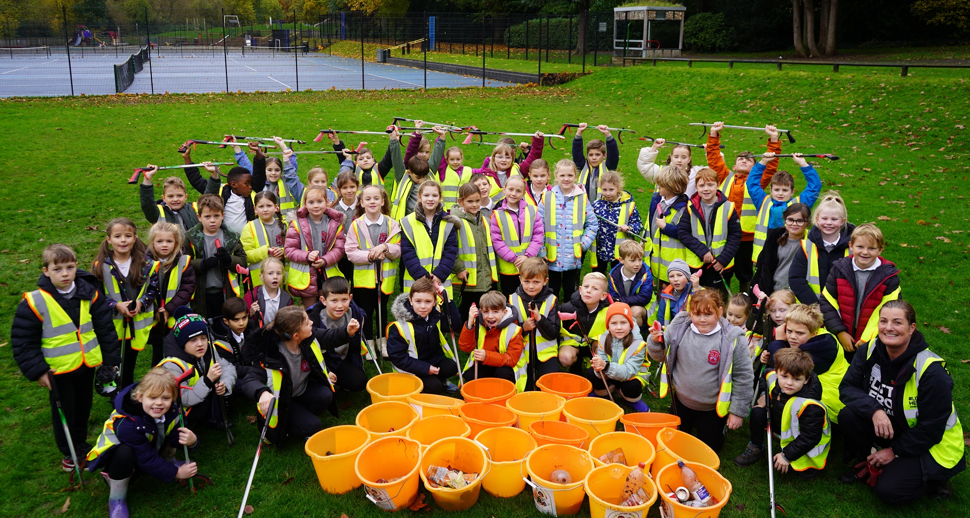 A group of children in a circle with litter pickers cheering
