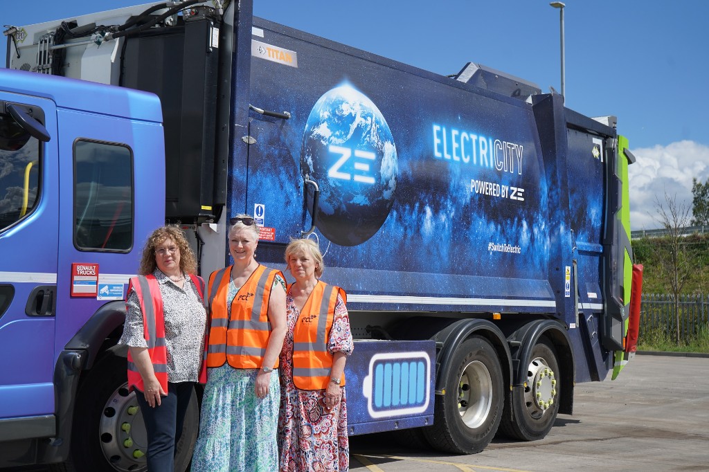 Three women stood in front of an electric bin lorry