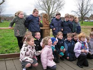 Children from the local area taking a photo with a tree carving sculpture