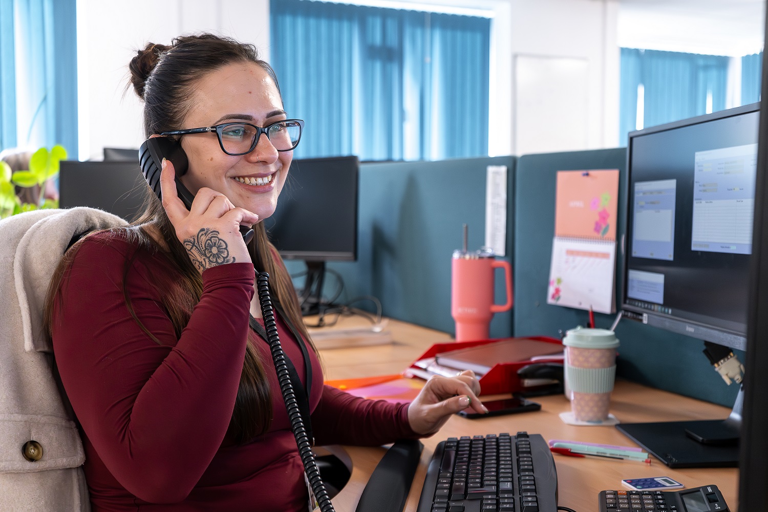 A woman taking a phone call at her desk