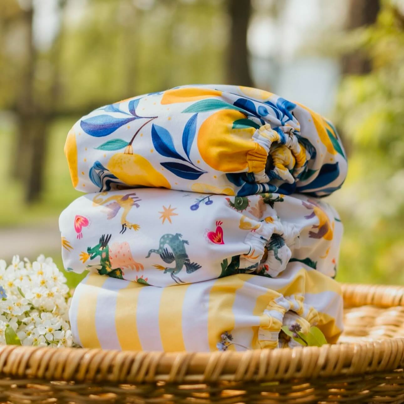Colourful image of a stack of a reusable nappies resting in a wicker basket, outside