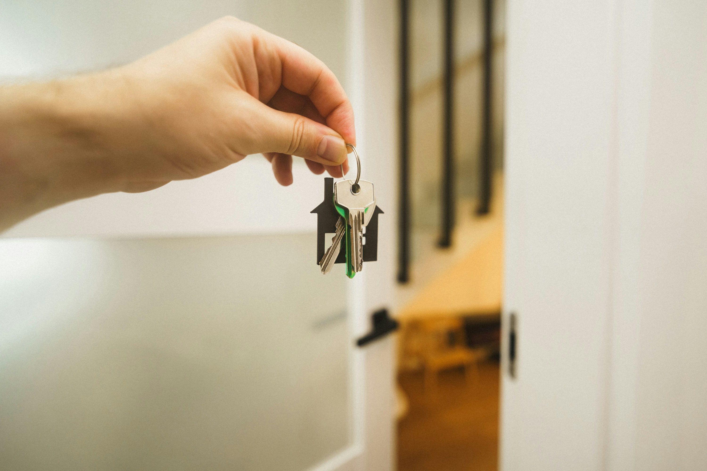 Person holding up keys at the entrance of a property