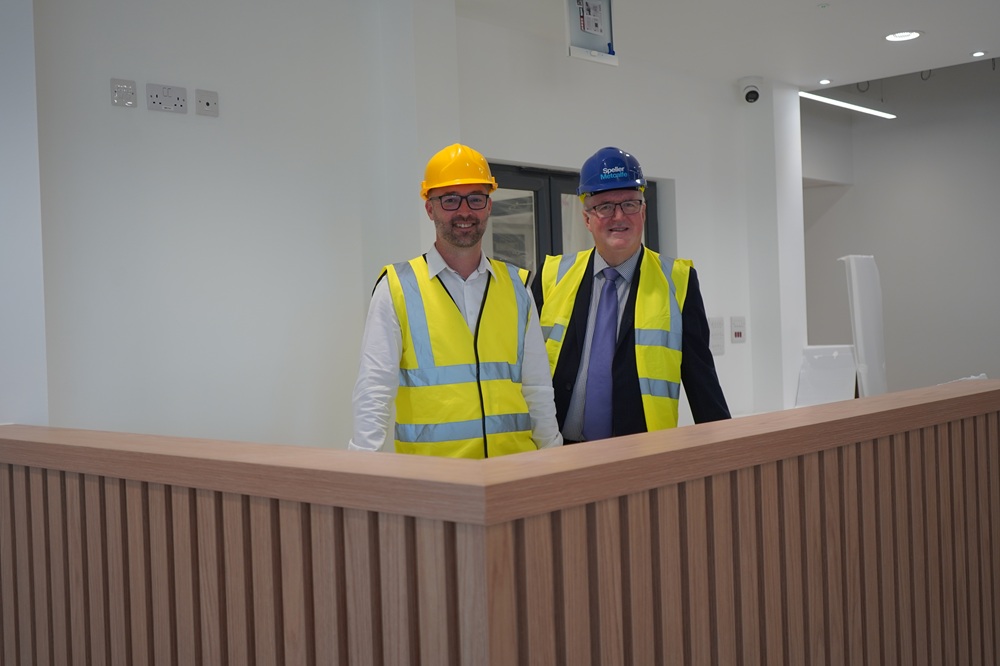 Two men in high vis and hard hats behind a counter