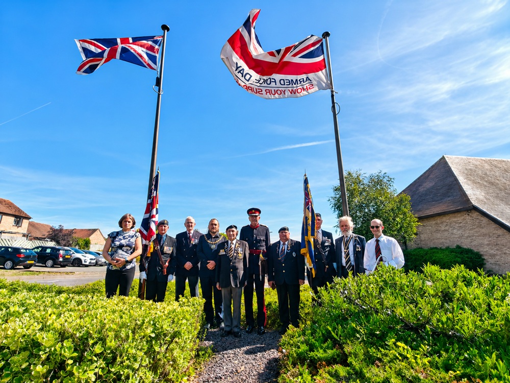 A group of people stood between flag poles.