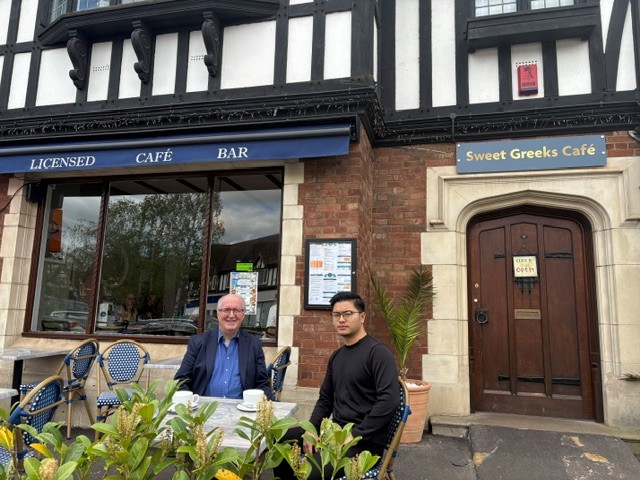 Cllr Morris and a man sat at a table outside Sweet Greeks Cafe in Droitwich Spa