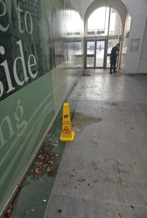 Dirty shopping centre floor with a man mopping in the distance