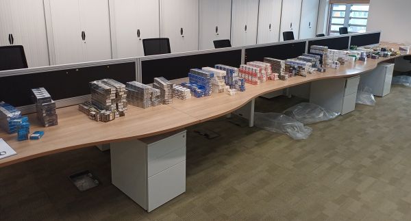 A row of cigarettes and vapes on a long table.