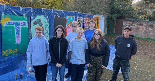 Young people stood next to the street art that they created