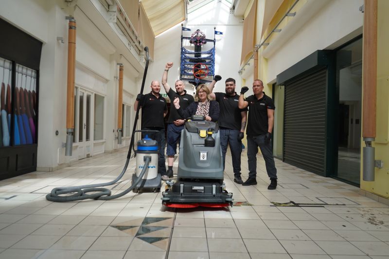 A group of people stood cheering behind a pressure washer