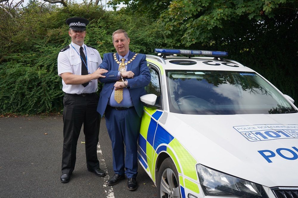A police officer and Cllr Raphael stood in front of a police car
